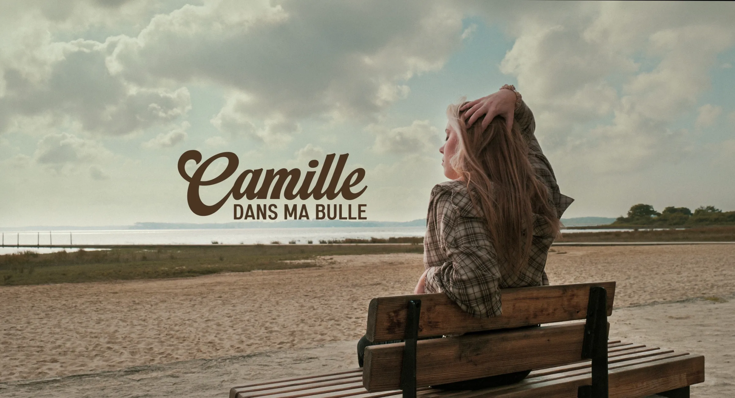 Camille assise sur un banc face à la mer — bannière du single « Dans ma bulle »