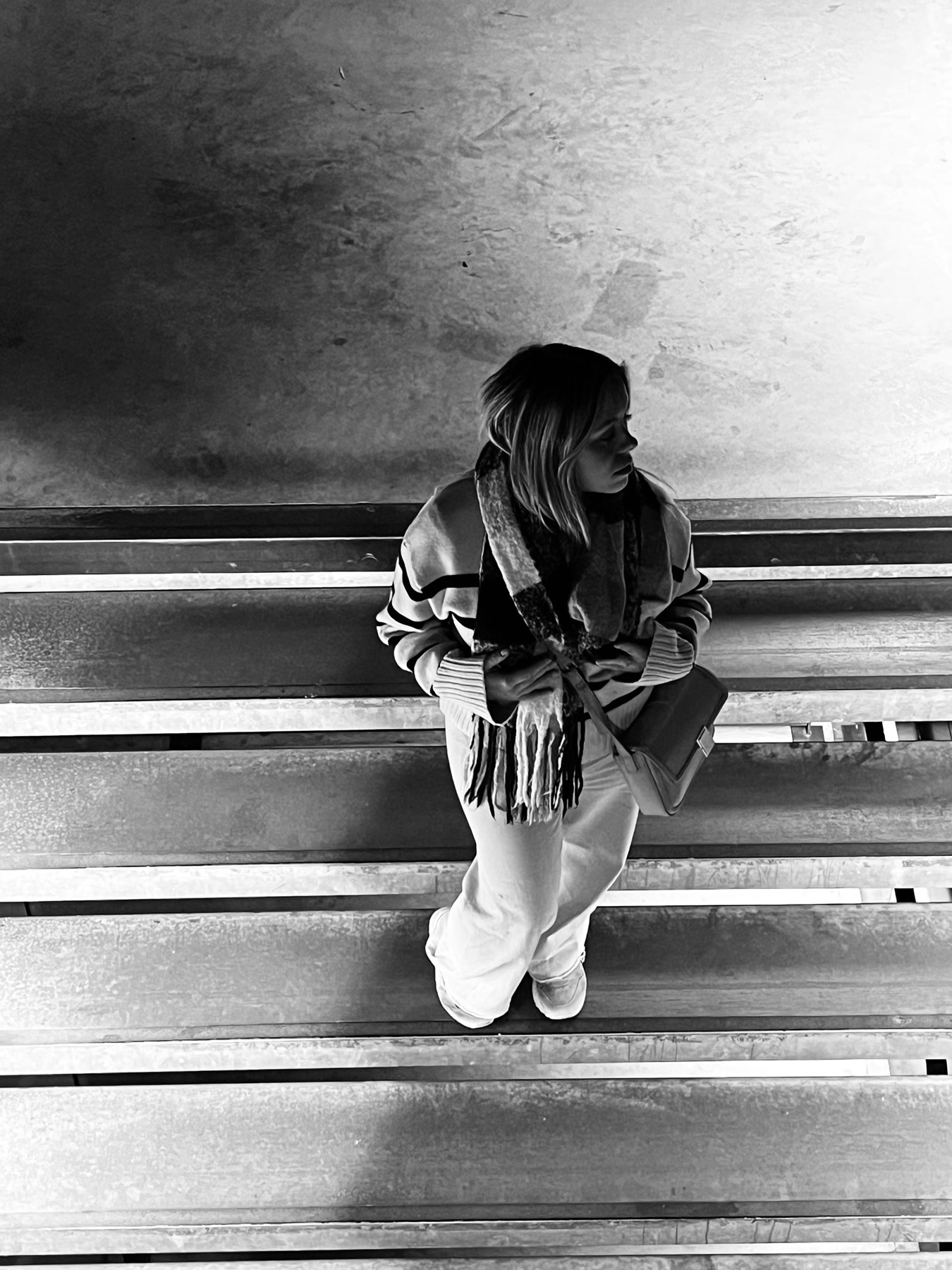 Camille assise sur des gradins de béton